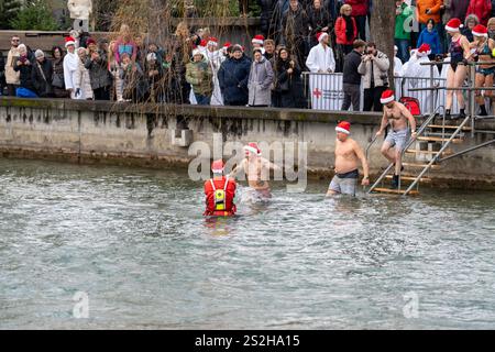 Thun, Schweiz - 8. Dezember 2024: Die Weihnachtsklauseln tauchen jährlich während des Weihnachtsmarktes in das kalte Wasser der Aare Stockfoto