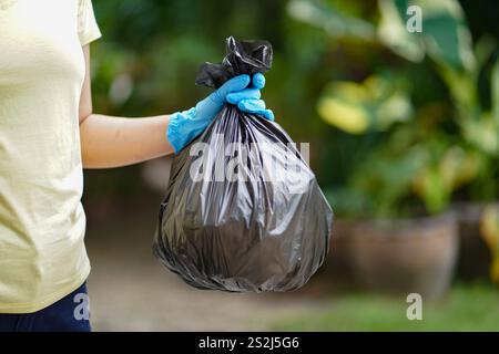 Freiwillige Wohltätigkeitsfrau Hand hält Müll schwarze Tasche und Plastikflaschenmüll für Recycling für Reinigung im Park Freiwilligenkonzept Reuse und vo Stockfoto