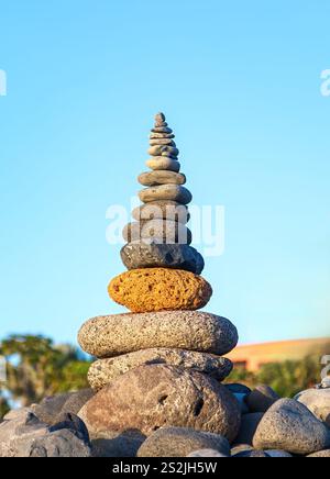 Ein ausgeglichener Stapel glatter Steine steht vor einer ruhigen Himmelskulisse, die Harmonie, Ruhe und die zarte Kunst des Gleichgewichts symbolisiert. Stockfoto