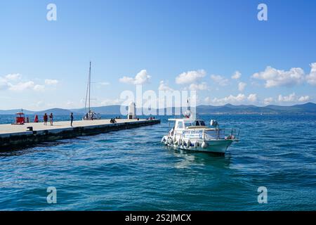 Zadar, Kroatien - 23. September 2024: Hafenmole von Zadar mit weißem Leuchtturm, türkisfarbenem Wasser und Ausflugsboot Stockfoto