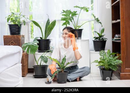 Die Frau trug orangefarbene Handschuhe und pflanzte Bäume im Haus. Stockfoto