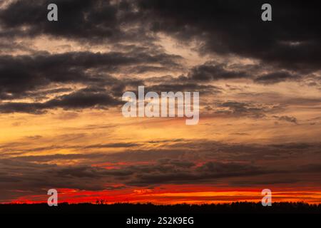 Erleben Sie den atemberaubenden und atemberaubenden Sonnenuntergang, der den Himmel über einem dramatischen bewölkten Horizont malt Stockfoto