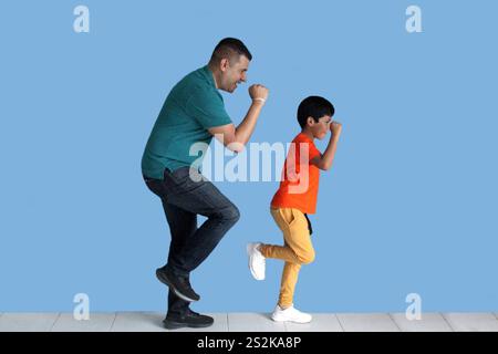 Geschiedener Alleinvater mit seinem 9-jährigen dunkelhäutigen Latino-Sohn tanzen als Zeichen von Sieg und Triumph beim Spielen und Spaß Stockfoto