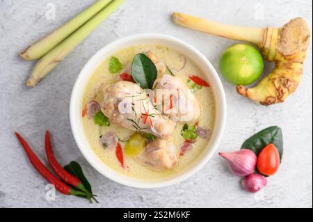 Tom Kha Kai in einer Schüssel mit Kaffir-Limettenblättern, Zitronengras, roten Zwiebeln, Galgant und Chili. Selektiver Fokus Stockfoto