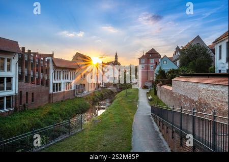 Ein malerischer Sonnenuntergang über einem bezaubernden Kanal in Donauworth, gesäumt von historischen Gebäuden. Bunte Häuser, eine kleine Brücke und üppiges Grün Stockfoto