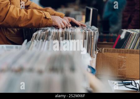 Männerhände suchen die Platten in einem Vinylladen. Kunden suchen nach Schallplatten. Schallplatten im Angebot. Stockfoto