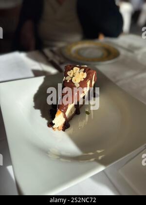 Käsekuchen mit Schokoladensoße, serviert bei Tageslicht im italienischen Restaurant Stockfoto