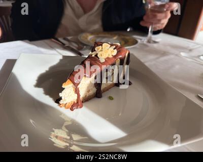 Käsekuchen mit Schokoladensoße, serviert bei Tageslicht im italienischen Restaurant Stockfoto