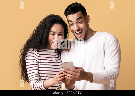 Coole App Aufgeregt arabischen Paar Blick auf Smartphone-Bildschirm in den Händen Stockfoto
