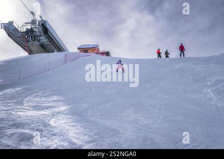 An einem hellen Tag genießt eine liebevolle Familie das Skifahren auf wunderschönen verschneiten Pisten, mit einem Skilift im Hintergrund, was unvergessliche Momente des Wintersports schafft, Montgenevre, Alpen, Frankreich Stockfoto