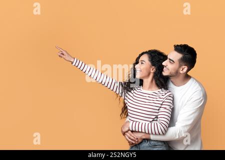 Familienangebot. Glückliche Arabische Ehegatten Umarmen Und Zeigen Beiseite Auf Copy Space Stockfoto