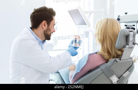 Beraded Doctor Zahnarzt zeigt jow Miniatur dem Patienten Stockfoto