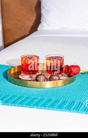 Zwei Cocktailgläser mit Erdbeeren mit Schokoladenüberzug auf einem Tablett im Bett Stockfoto