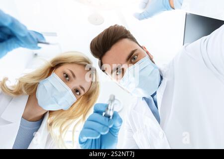 Zwei Zahnärzte in Gesichtsmasken und Gummihandschuhen bei der Behandlung Stockfoto