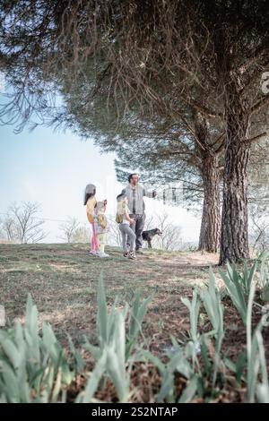 Vater mit drei Töchtern und einem Hund, der Bäume im Park beobachtet Stockfoto