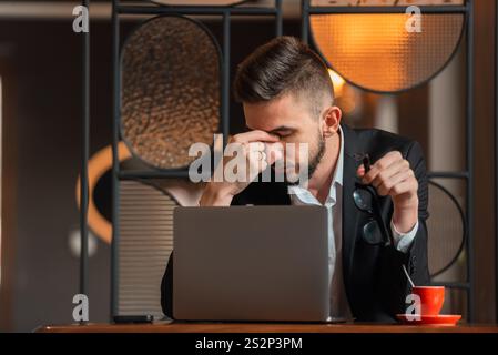 Ein Geschäftsmann arbeitet mit Überstunden und fühlt sich im Büro müde. Stockfoto