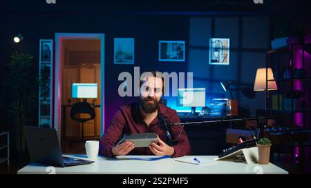 Fröhlicher Internet-Star, der die Technologie-Überprüfung von tragbaren Bluetooth-Lautsprechern für Online-Plattformen-Kanal macht, Nahaufnahme. Fröhlicher Influencer, der seinem Zuschauer, Kamera B, ein Musikspielgerät vorstellt Stockfoto