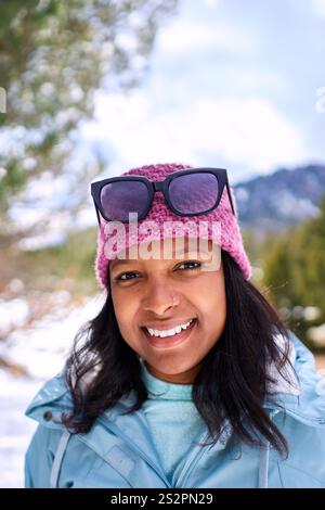 Porträt einer jungen Afroamerikanerin in einem verschneiten Wald, die den sonnigen Tag im Freien genießt. Stockfoto