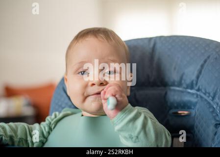 6 Monate altes Baby, das mit dem Trainingslöffel feste Nahrung anfängt Stockfoto