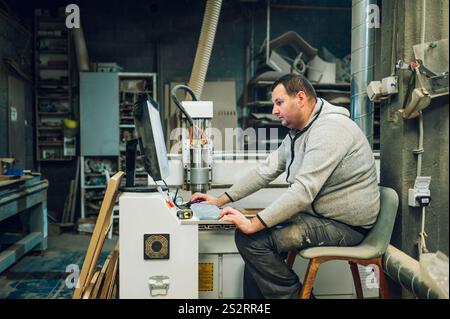 Porträt eines Industriearbeiters, der cnc-Bohrmaschinen in der Holzbearbeitungsindustrie bedient. Herstellerwerkstatt und Möbelfabrik Konzept. Co Stockfoto