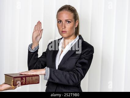 Eine Frau sagt als Zeugin in einem Gerichtsverfahren aus. Sie ist vereidigt und schwört auf die Bibel. Österreich Stockfoto