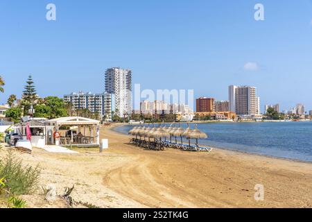 Strohschirme und Liegestühle stehen am Sandstrand von La Manga, im Hintergrund ragen Resorthotels und Apartments, Playa de Cavanna Stockfoto