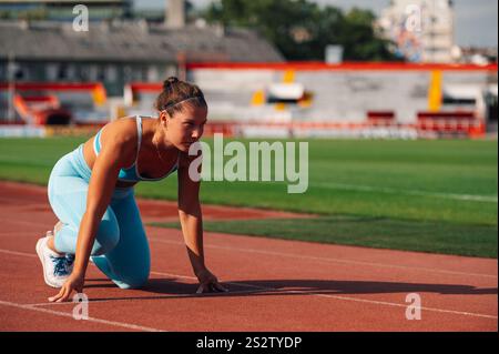 Porträt einer Sprintersportlerin, die sich auf ein Rennen auf einer Schottenrennbahn im Stadion vorbereitet. Gesunder Sport-Lifestyle. Fitness und Workout Stockfoto