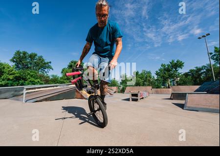 Ein erfahrener urbaner Radfahrer führt Freestyle-Tricks und Stunts auf seinem bmx in einem Skatepark aus. Ein Mann mittleren Alters übt Tricks und Stunts Stockfoto