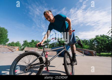 Ein altmodischer Cooler spielt Freestyle-Tricks und Stunts in einem Skatepark. Ein Freestyle-reifer, tätowierter bmx-Fahrer übt Tricks und Stunts an Stockfoto