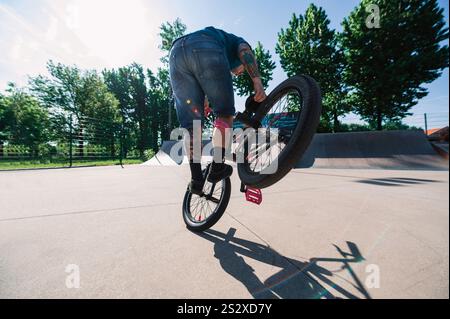 Ein urbaner reifer Mann balanciert auf seinem bmx, während er Freestyle-Tricks und Stunts übt. Ein Mann mittleren Alters führt Freestyle Bike Tricks in A s durch Stockfoto