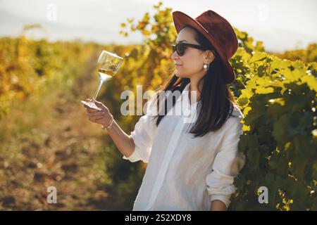 Frau mit Hut und Sonnenbrille, die ein Glas Wein hält Stockfoto