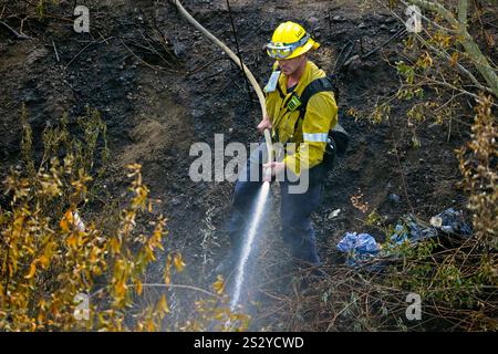 LOS ANGELES COUNTY, KALIFORNIEN, USA - 13. Dezember 2024 - die Feuerwehrleute der Cal Fire sprühen Wasser auf einen Teil eines brennenden Canyons im Los Angeles County, Kalifornien Stockfoto