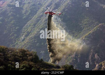 LOS ANGELES COUNTY, KALIFORNIEN, USA – Dezember 2024 – Ein spezialisierter Löschhubschrauber lässt Wasser auf einen Canyon im Los Angeles County, Kalifornien, fallen. Stockfoto