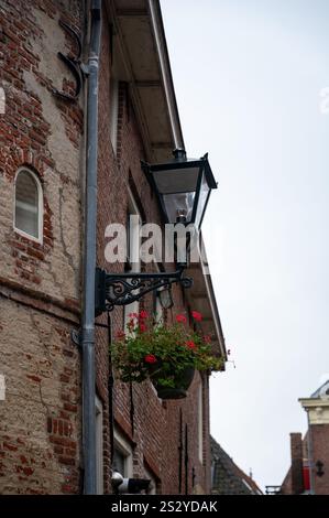 Alte schwarze Straßenlaterne an einem Haus in den Niederlanden, mit einem hängenden Blumenkorb Stockfoto