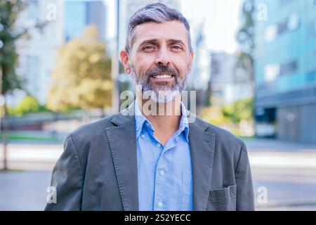 Selbstbewusster Geschäftsmann mittleren Alters, der draußen lächelt Stockfoto