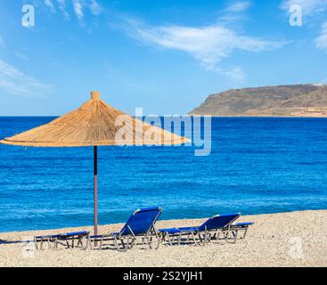 Sommer morgen kiesiger Strand mit liegen und Sonnenschirm strohig (Borsh, Albanien). Stockfoto