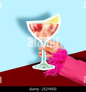 Weibliche Hand in einem festlichen rosa Anzug mit Federgriffen und ausgeschnittenem süß-saurem Cocktail auf hellgrünem und tiefrotem Hintergrund. Stockfoto