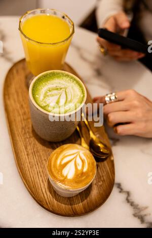 Heiße Getränke und frischer Saft auf einem Holztablett in einem gemütlichen Café. Stockfoto
