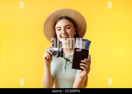 Frau mit Tickets, Pass und Vintage-Kamera auf orangem Hintergrund Stockfoto