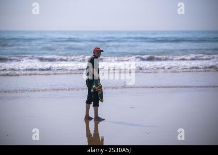 Älterer Mann, der am Strand spazieren sah Stockfoto
