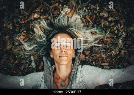 Eine Frau, die freudig die Schönheit der Natur umgibt, umgeben von Herbstlaub Stockfoto