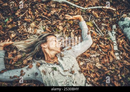 Eine Frau, die freudig die Schönheit der Natur umgibt, umgeben von Herbstlaub Stockfoto