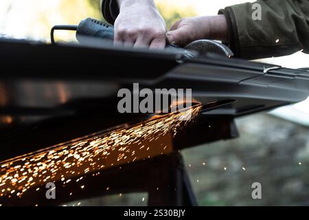 Erwachsene, weiß, männlich, schneiden Metall mit einem Schleifgerät Stockfoto