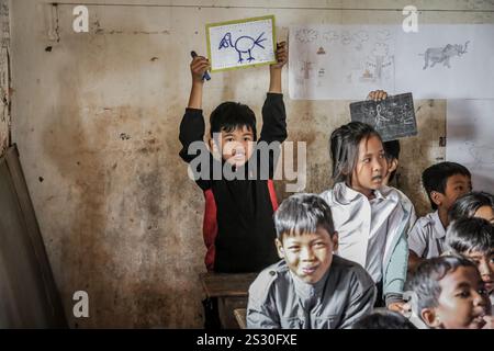 Provinz Kandal, Kambodscha. Januar 2025: Ein Schuljunge ohne Uniform zeigt im Unterricht eine Zeichnung auf Schiefer. Zurück zur Schule für Khmer-Kinder in Phnom Penh Vororten, später als in anderen südostasiatischen Ländern. Gestern war ein Feiertag, als Kambodschaner am 7. Januar 1979 den Sieg über den Völkermord feierten, mit der Befreiung der Hauptstadt und dem Fall des Pol Pot-Regimes. Obwohl das Land überwiegend buddhistisch ist (93 % bis 97 %), umfassen die „Winterschulferien“ Weihnachten, den kambodschanischen Friedenstag am 29. Dezember, das Internationale Neujahr und den Siegestag. Quelle: Kevin Izorce/Alamy Live News Stockfoto