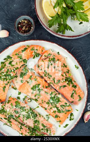 Frischer Lachsfischsteaks in grüner Knoblauchmarinade zum Backen bereit. Stockfoto