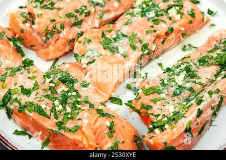 Frischer roher Lachsfilet Fisch in Knoblauchkräutern mariniert zum Backen bereit. Nahaufnahme. Stockfoto