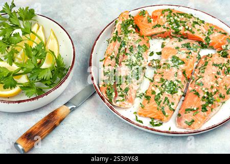 Frischer roher Lachsfilet in grüner Knoblauchmarinade zum Backen bereit. Stockfoto
