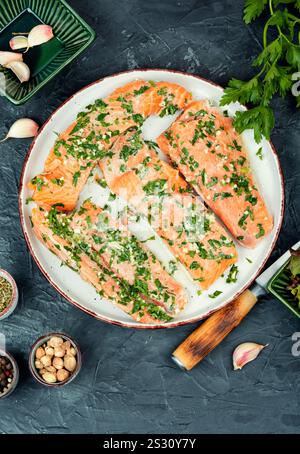 Frischer Lachsfischsteaks in grüner Knoblauchmarinade zum Backen bereit. Stockfoto