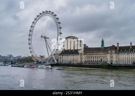 Legendäres London Eye Riesenrad an einem bewölkten Tag – malerischer Blick auf die Themse mit Booten und historischer Architektur im Herzen von London, perfekt Stockfoto