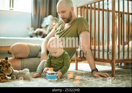 Lernen, spielen und entwickeln, Mann und Baby im Kinderzimmer, neuer Vater und Kind kleben mit Spielzeug im Spielzimmer. Familie, Liebe und junger Vater mit Stockfoto